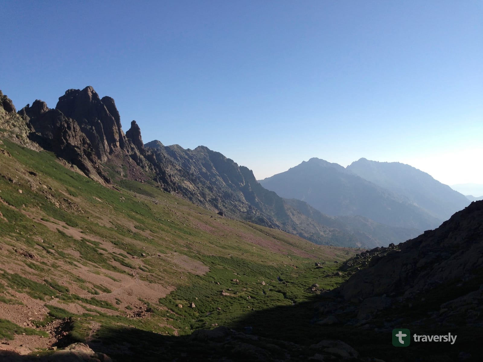 Corsica's high interior peaks, seen from a green valley in fading evening light.
