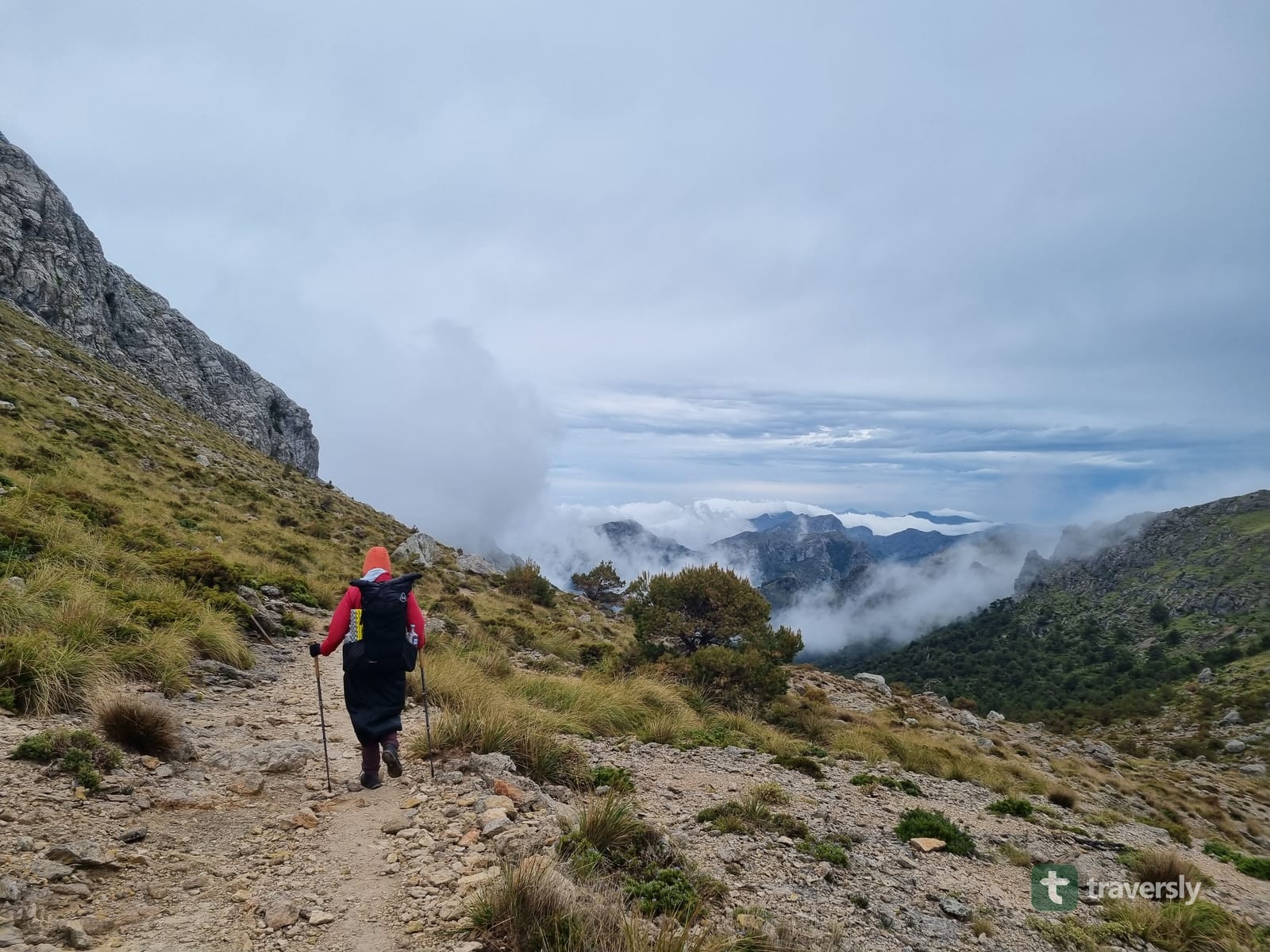 A hiker walks into low cloud on an exposed grassy ridge in the Serra de Tramuntana, Mallorca.